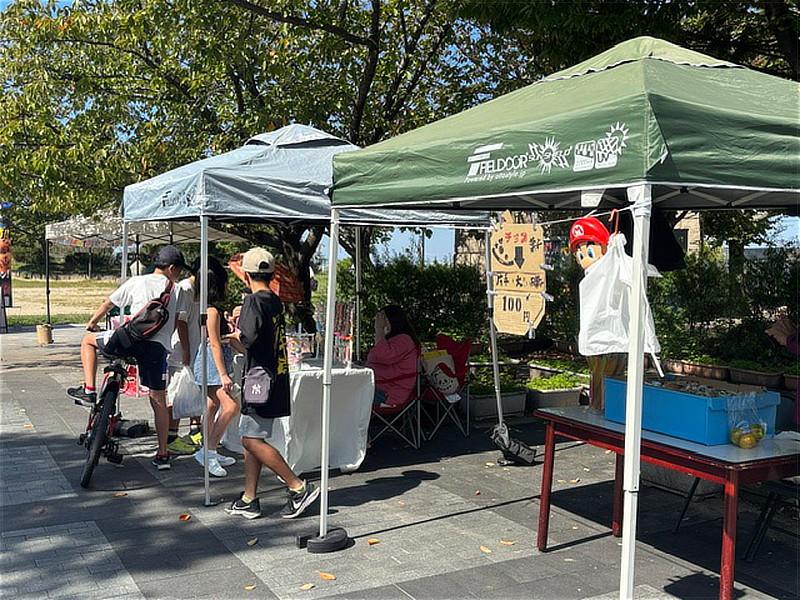 東石切公園で開催されたSAKURAZAKAマルシェの会場風景。キッチンカーやテントが並び、来場者が買い物を楽しんでいる。